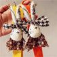 Close-up of beige fabric rabbit keychain showing stitched eyes and nose details