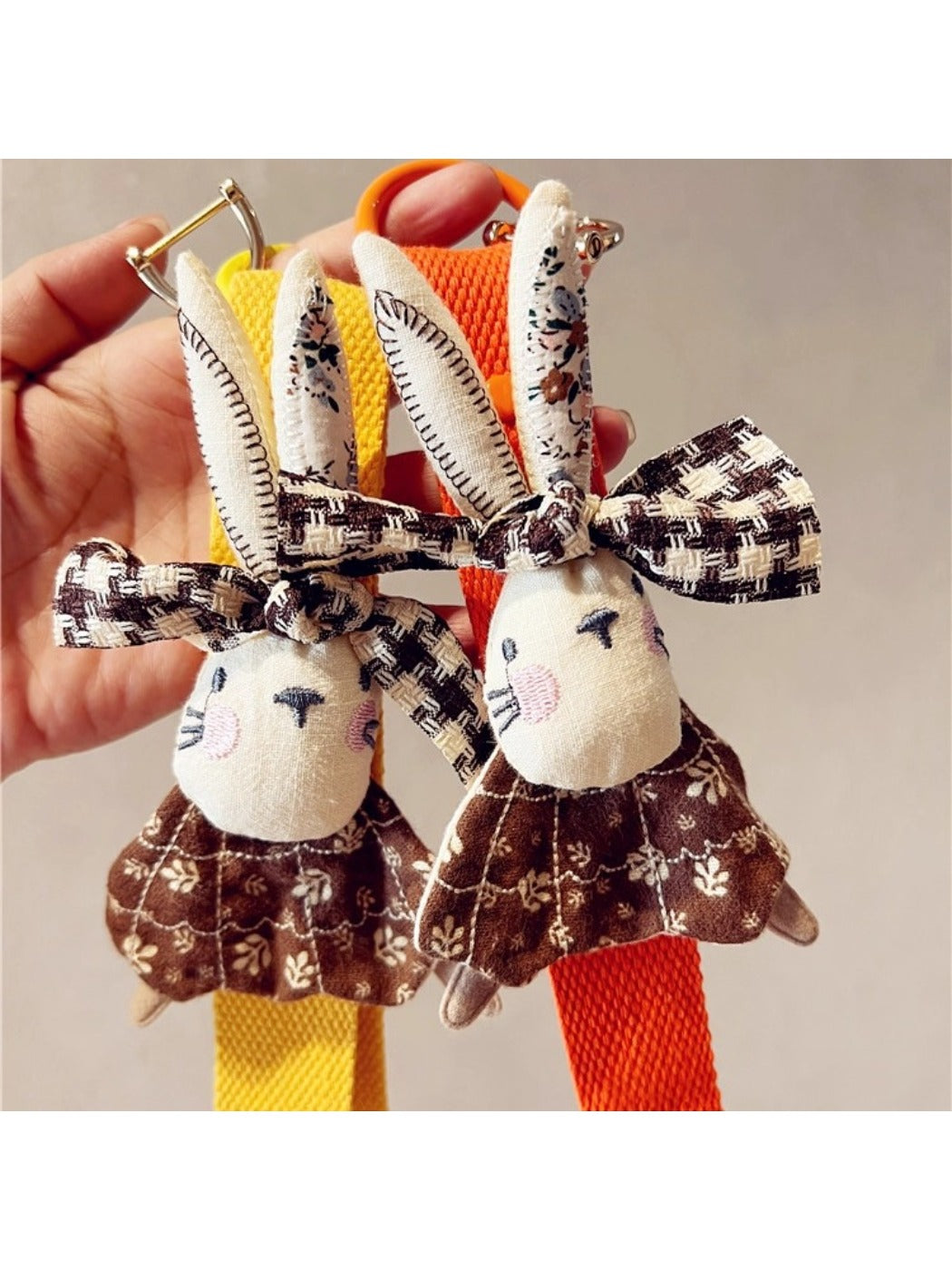 Close-up of beige fabric rabbit keychain showing stitched eyes and nose details