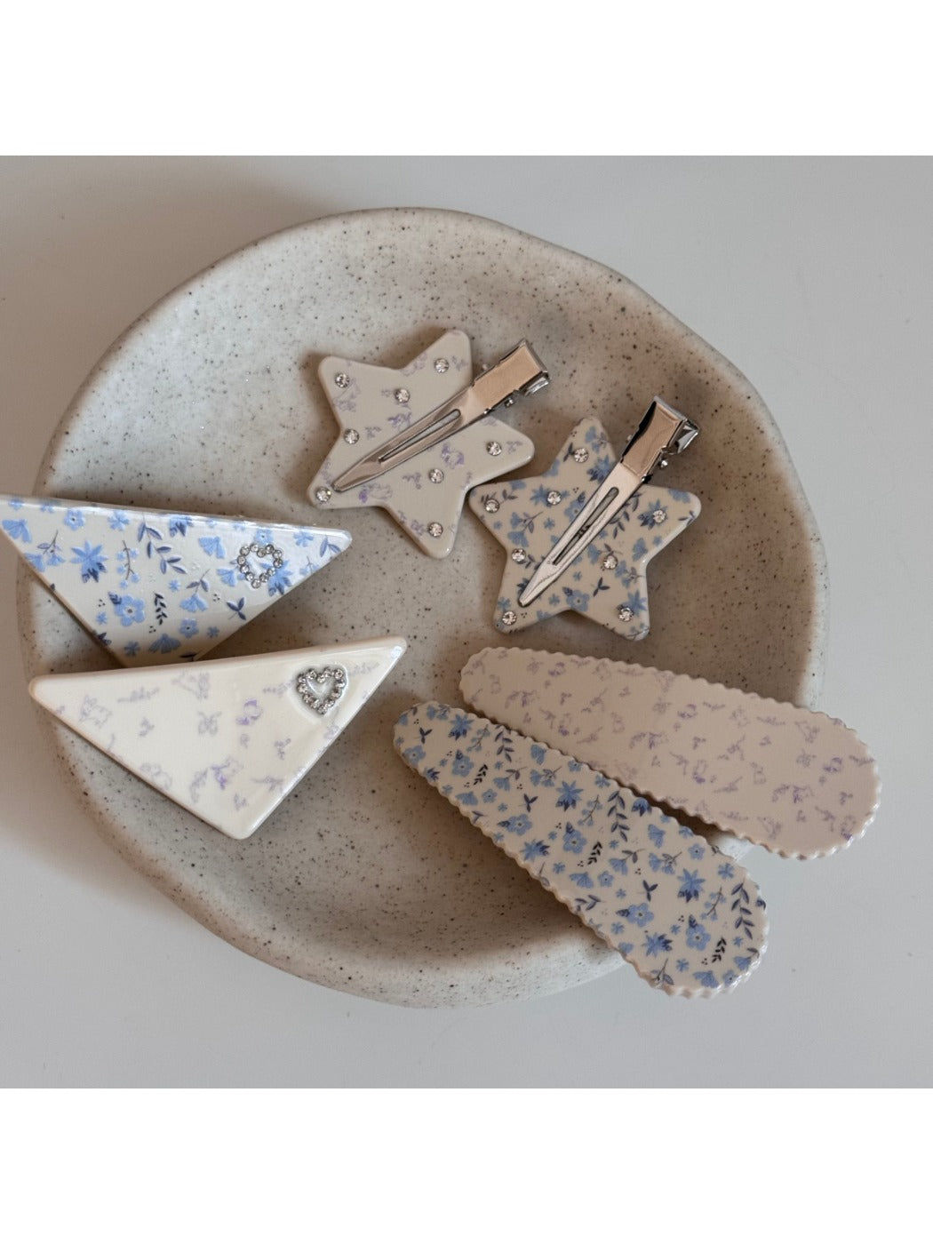 Beau hair clip held in hand displaying size and triangular shape with star print