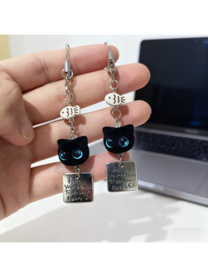 Close-up of blue eyed black cat keychain showing textured fur and eyes