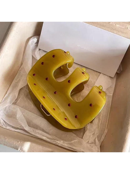 Close-up of yellow Beau claw clip showing curved teeth and polka dot pattern
