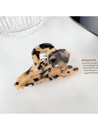 Beau colorful floral hair claw clip featured in lifestyle setting with plants