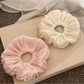 Close-up of a solid color satin ruched scrunchie with smooth texture