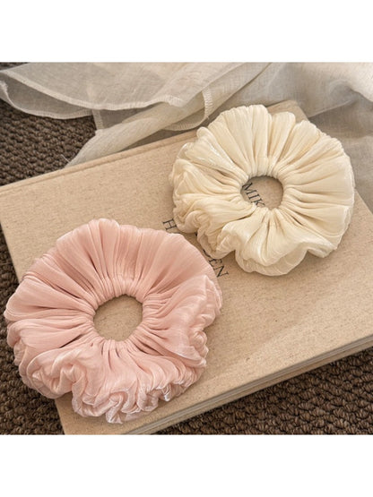 Close-up of a solid color satin ruched scrunchie with smooth texture