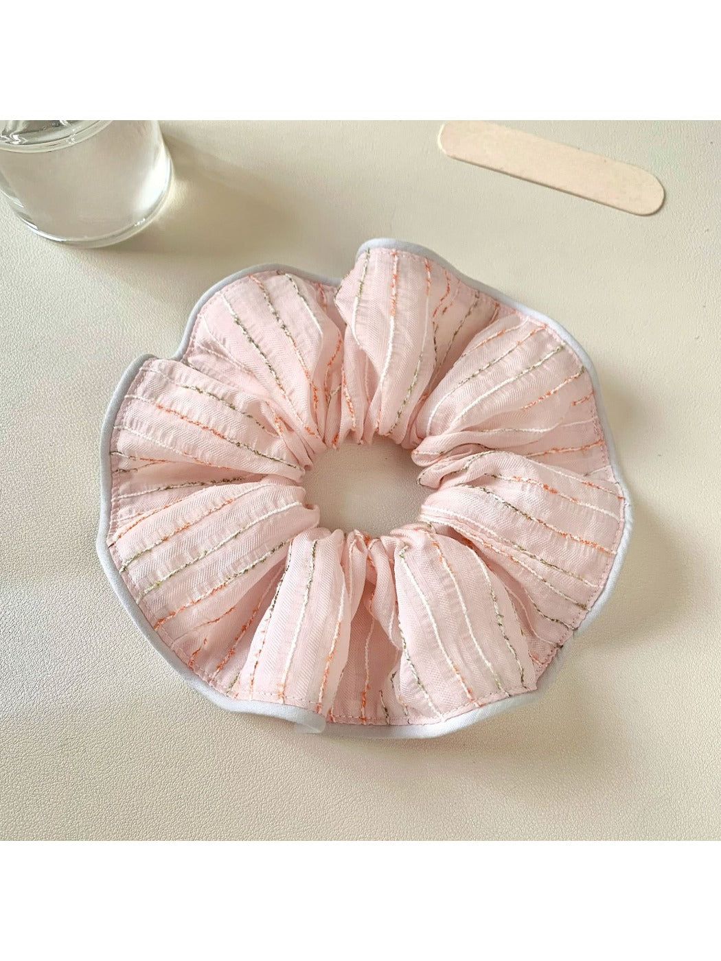 Pink striped hair scrunchie wrapped around a ponytail
