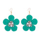 Raffia flower-shaped earrings arranged with natural elements like dried flowers and leaves