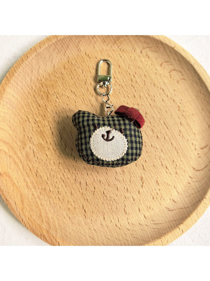 Bear charm keychain attached to a metal hook on a wall