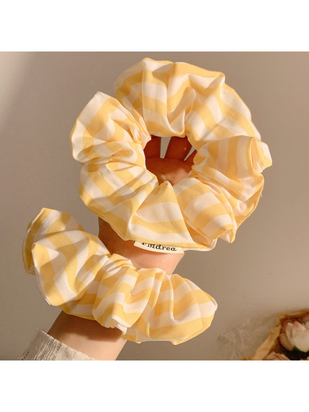 Yellow scrunchie with thin white stripes on a plain background