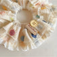 Scrunchie worn on wrist featuring vibrant multicolor polka dots