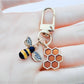 Close-up of bee and honeycomb shaped keychain on white background