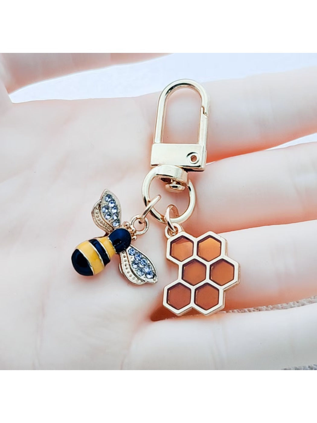 Close-up of bee and honeycomb shaped keychain on white background
