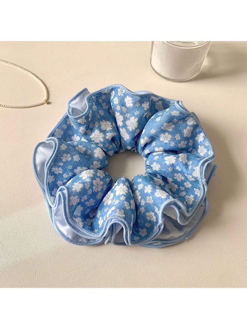 Close-up of blue floral scrunchie showing detailed fabric texture and pattern