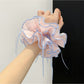 Pink bow print scrunchie wrapped around a ponytail on a model