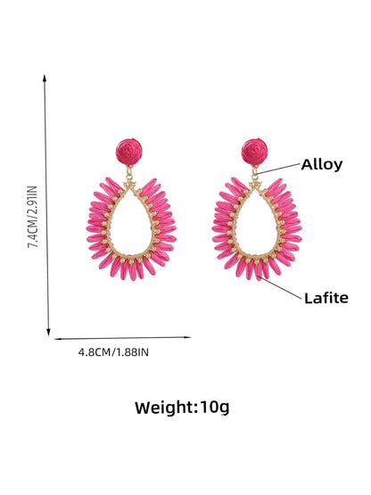 Pair of minimalist oval raffia drop earrings displayed on a beige fabric surface