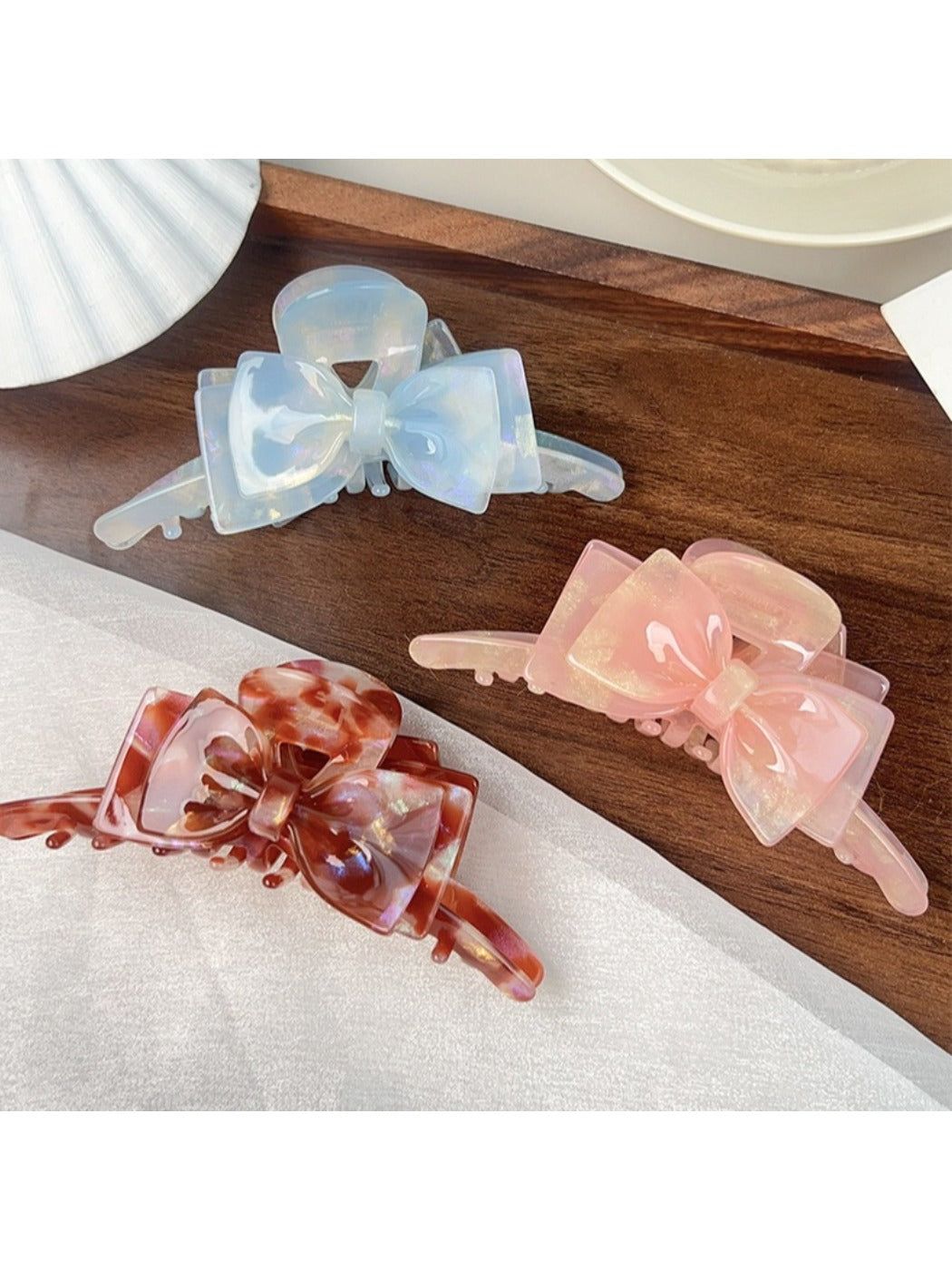 Beau double layer bow hair claw clip held in hand showing size and scale