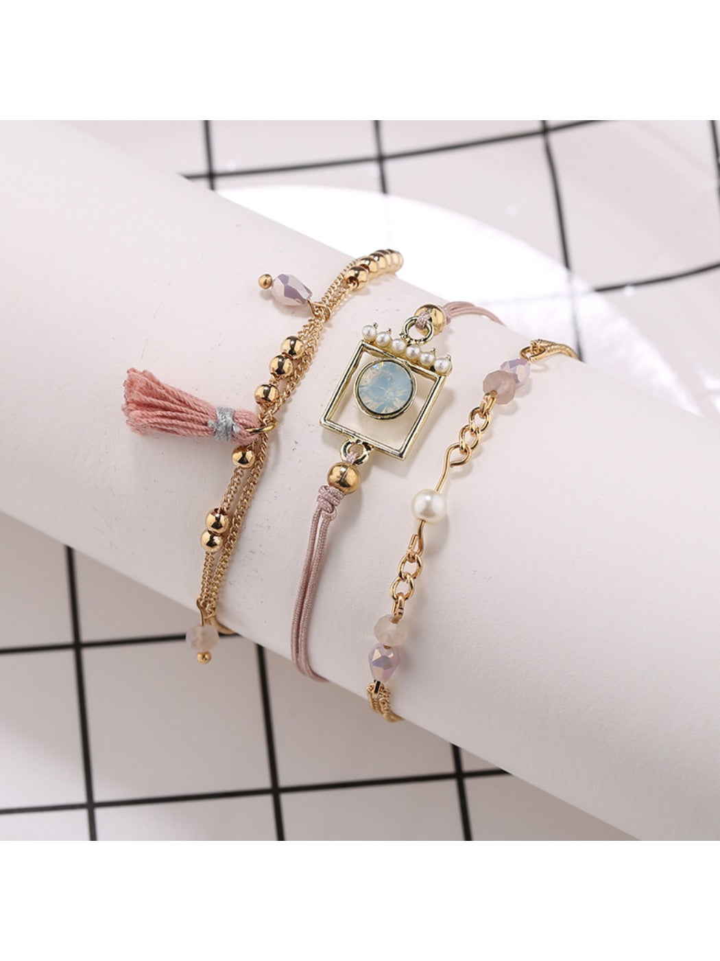 Lovra bracelet with gold tassel pendant and small round beads in natural light