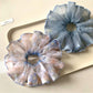 Pink scrunchie with minimalist abstract print displayed on a wooden surface