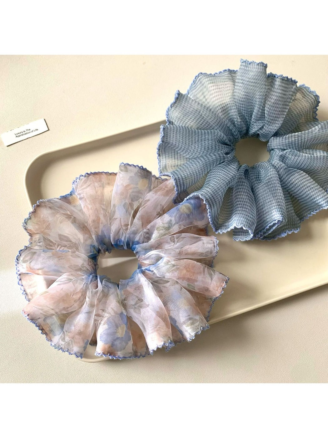 Pink scrunchie with minimalist abstract print displayed on a wooden surface