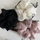 Pink tulle scrunchie with ribbon bow displayed on a wooden surface