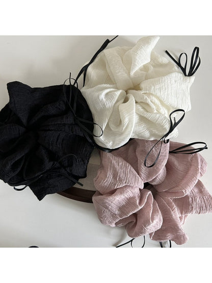 Pink tulle scrunchie with ribbon bow displayed on a wooden surface
