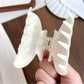 Beau hair claw clip holding thick brown hair in a half-up style