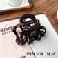Beau claw clip in matte black, resting on a wooden surface