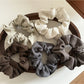 Close-up of Gifty striped scrunchie with simple white and beige stripes