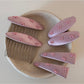 Pink bow hair clip with a soft fabric texture on a white background
