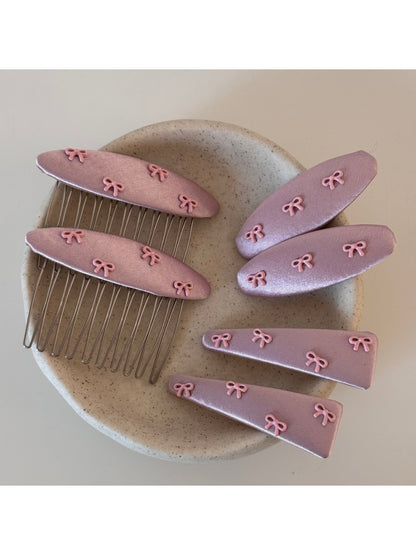 Pink bow hair clip with a soft fabric texture on a white background