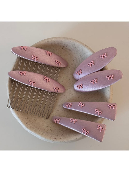 Pink bow hair clip with a soft fabric texture on a white background