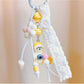 Front view of a cute cat shaped keychain with a smiling face and pink ears
