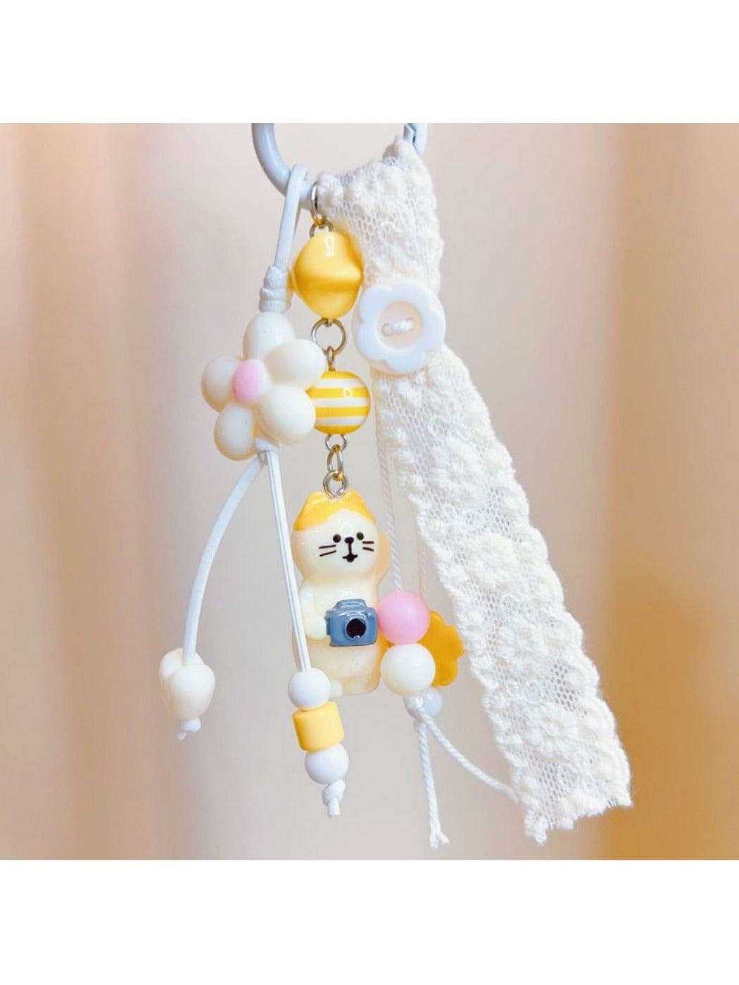 Front view of a cute cat shaped keychain with a smiling face and pink ears