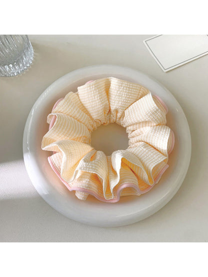 Pink ruffle beige scrunchie displayed on a wooden surface