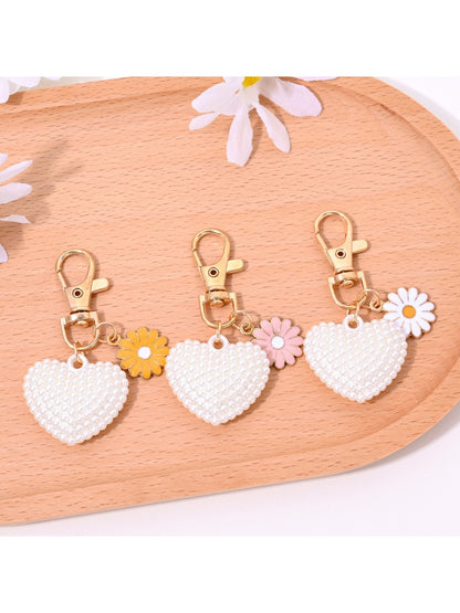 Red leather heart shaped keychain hanging from a gold keyring on a white surface