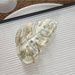 Beau delicate leaf shaped hair claw clip next to green leaves for aesthetic contrast