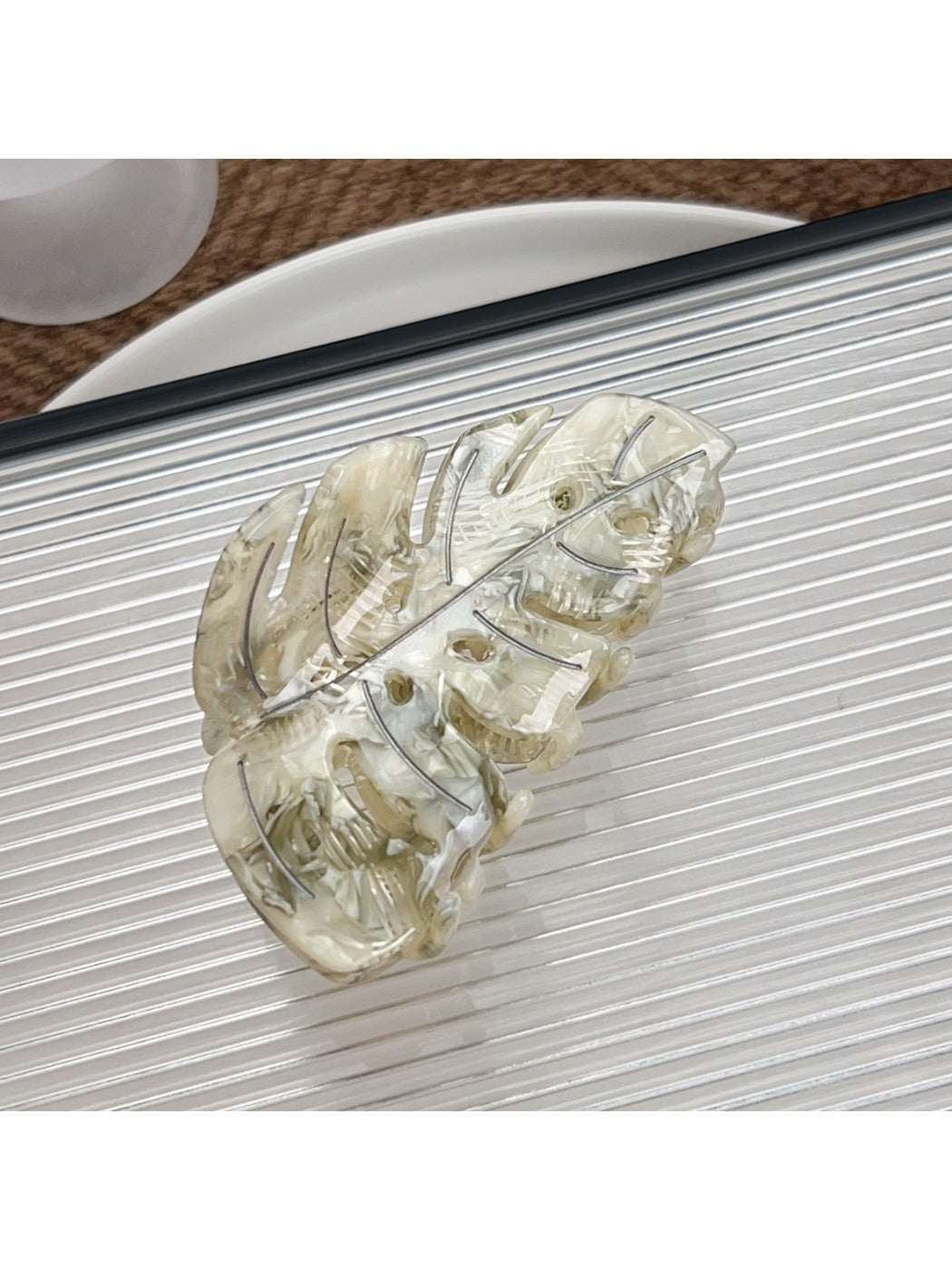 Beau delicate leaf shaped hair claw clip next to green leaves for aesthetic contrast