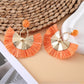 Earedge raffia fan earrings displayed with green leaves in background