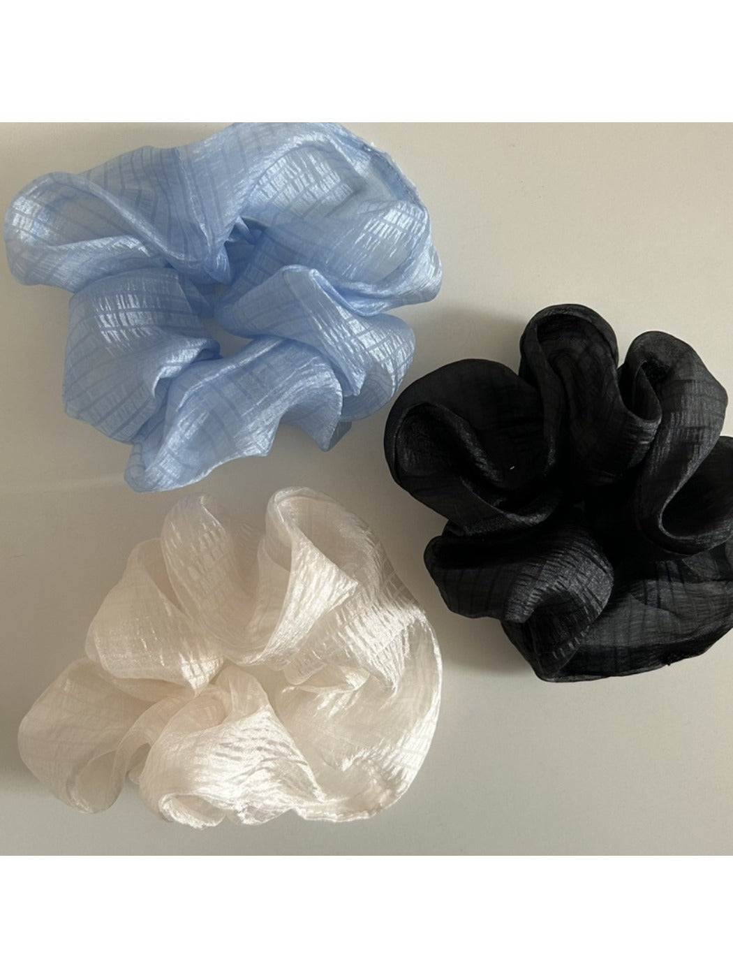 Sheer tulle scrunchie wrapped around a ponytail on dark hair
