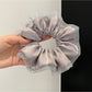 Pink satin scrunchie styled on a wrist as a bracelet accessory