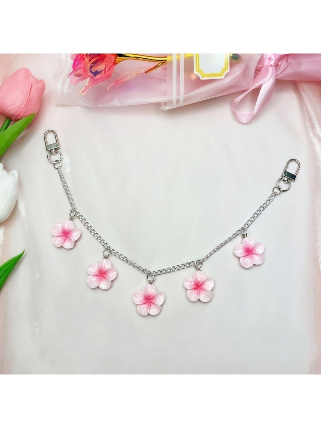 Flower pendant bag charm hanging from a black leather bag strap