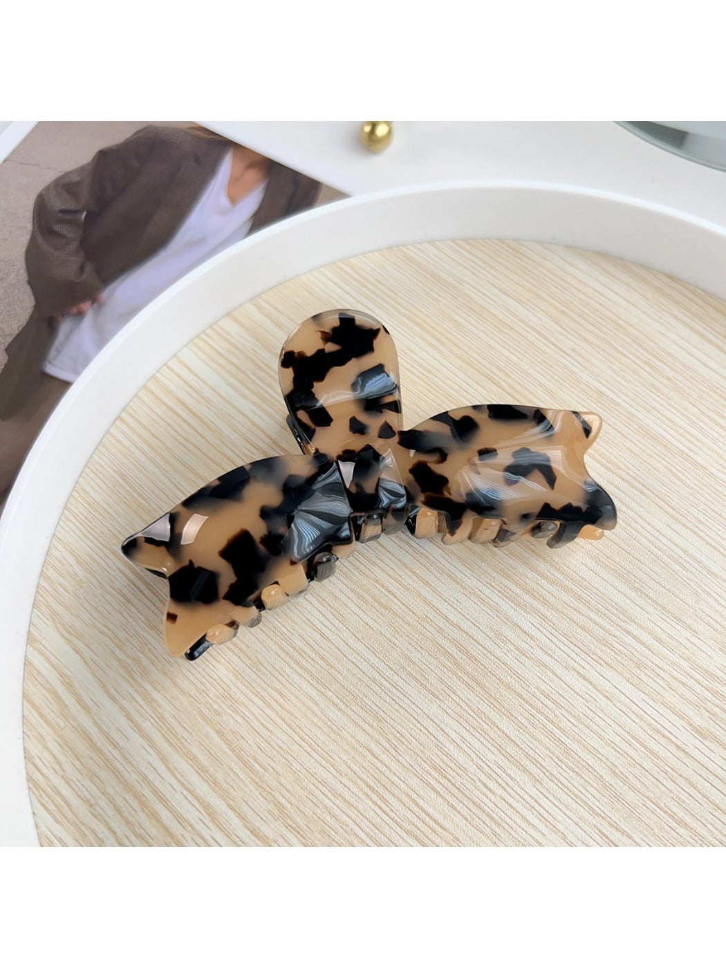 Beau hair claw clip in pastel pink placed on wooden surface