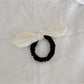 Gifty plaid hair tie with red bow detail placed next to matching plaid fabric