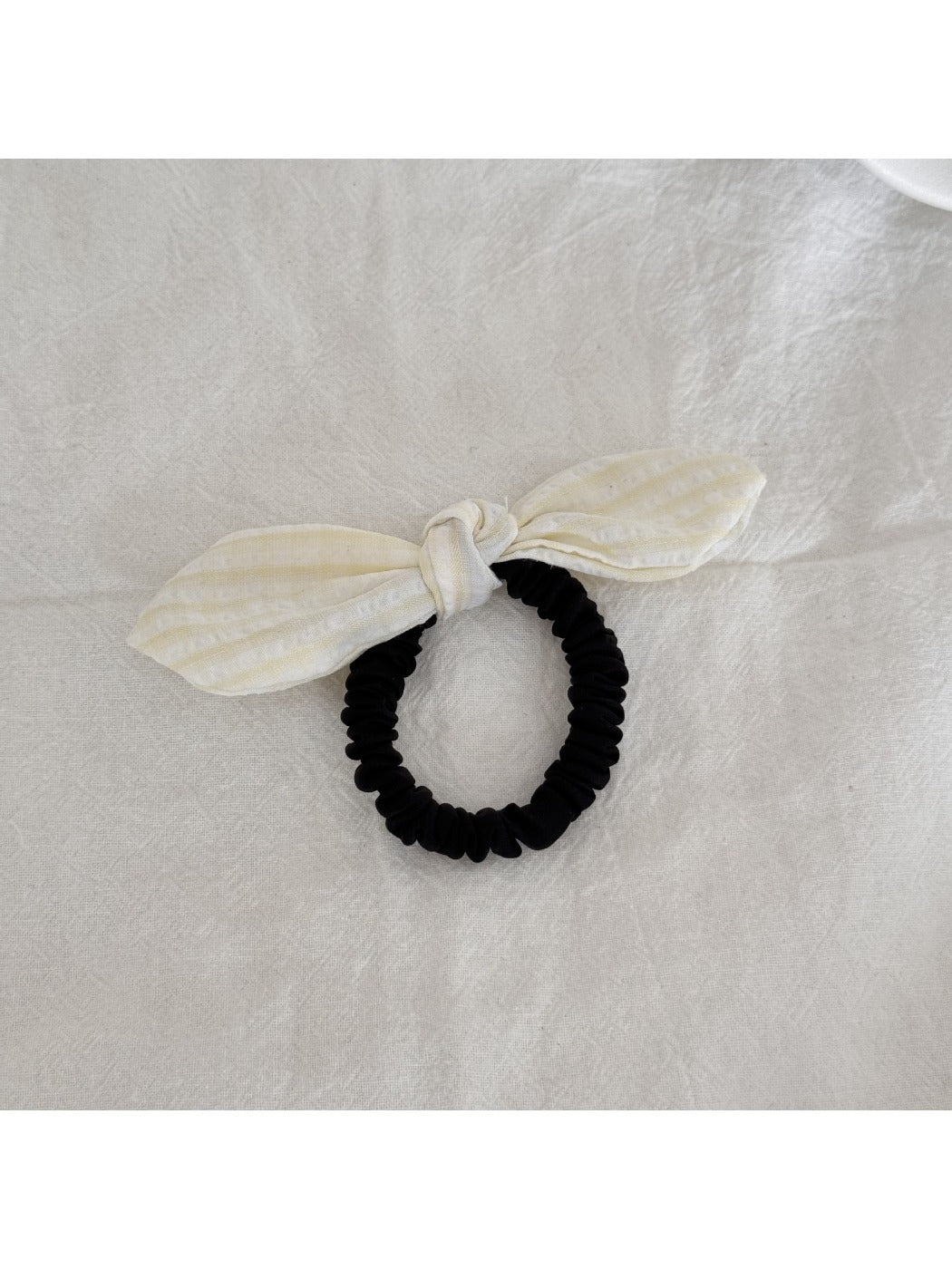 Gifty plaid hair tie with red bow detail placed next to matching plaid fabric