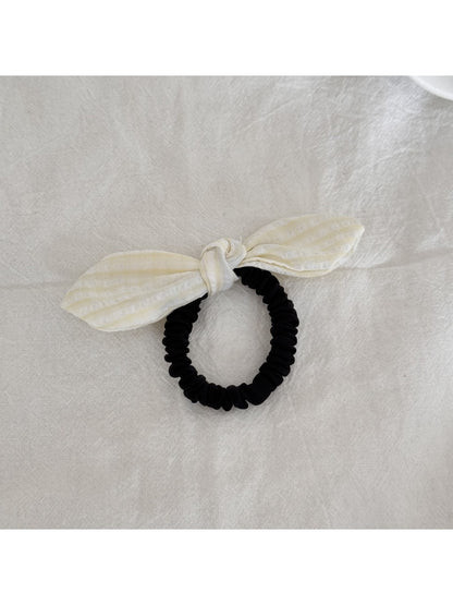 Gifty plaid hair tie with red bow detail placed next to matching plaid fabric