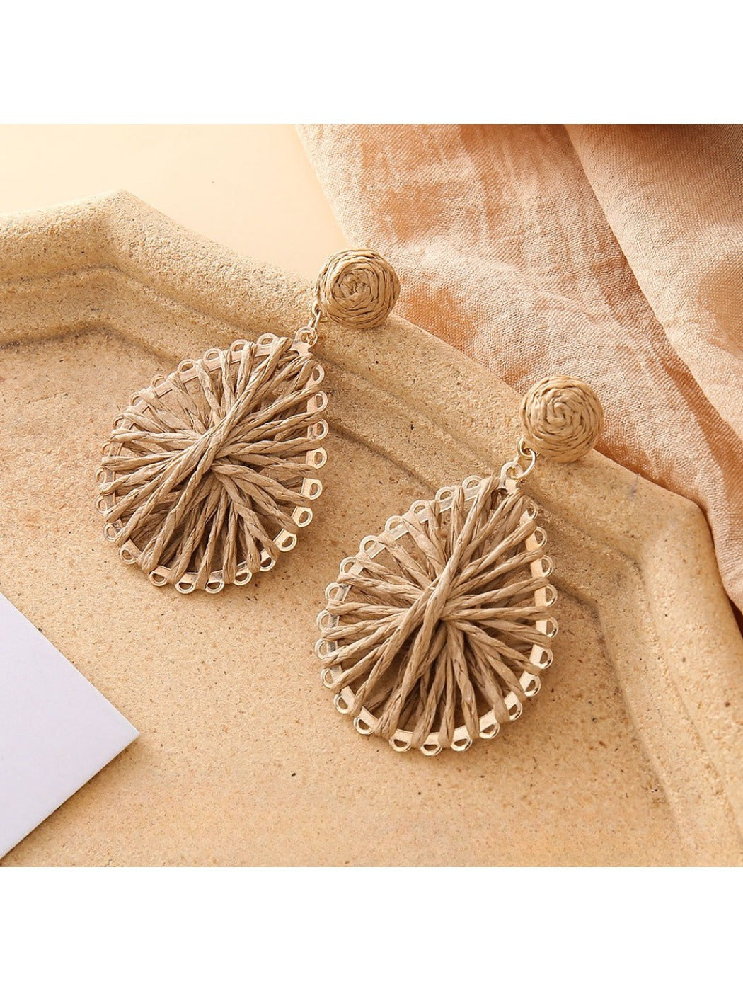Side view of lightweight raffia teardrop earrings showing natural fiber details