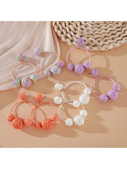 Close-up of Earedge raffia round ball earrings with woven natural fibers