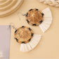Straw hat shaped earrings shown with natural lighting and shadows