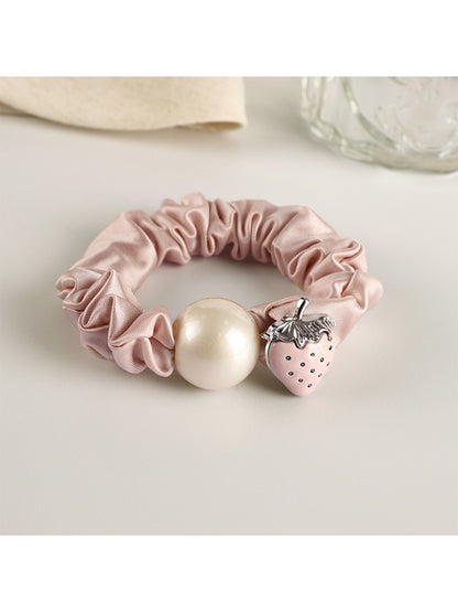 Hand holding the strawberry decorated hair tie showing its size and texture