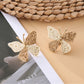 Silver butterfly drop earrings photographed against a light gray background