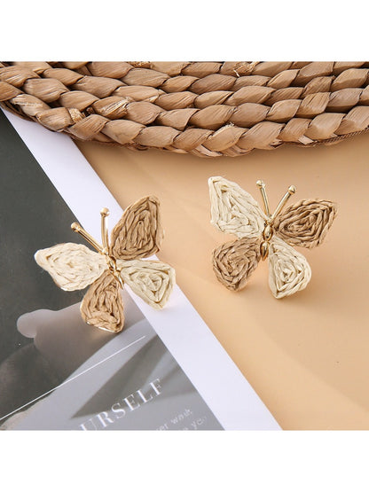 Silver butterfly drop earrings photographed against a light gray background